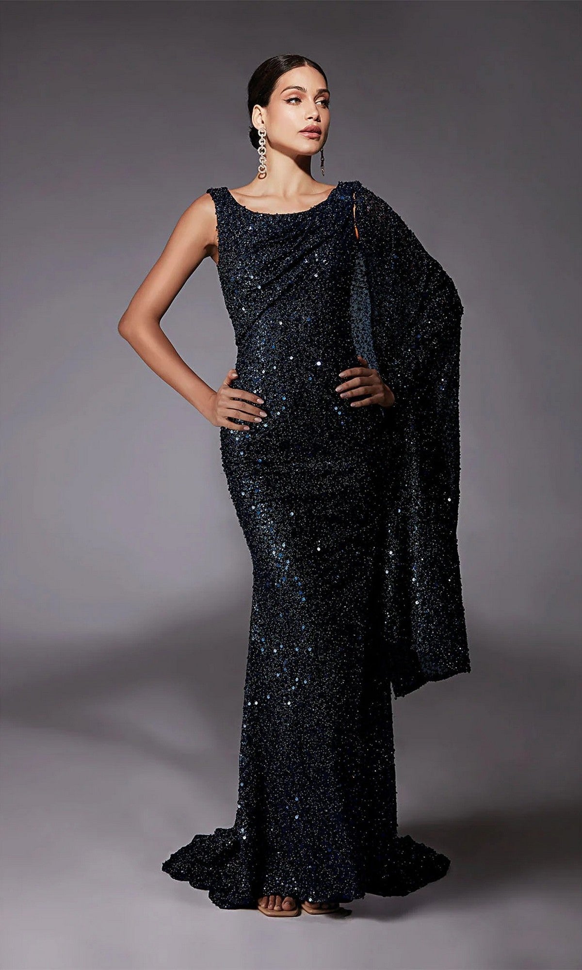 A woman poses in the Alyce 27772 long formal dress in midnight, featuring sequin beading and a matching draped shawl, set against a plain gray background.